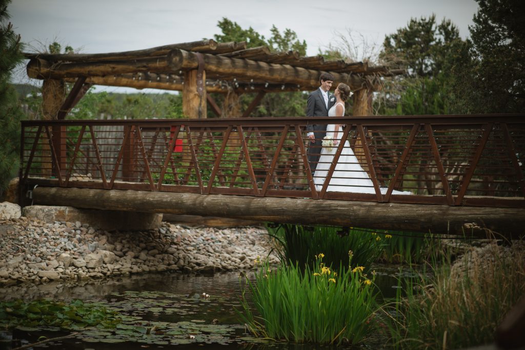 Bride and groom pose on bridge