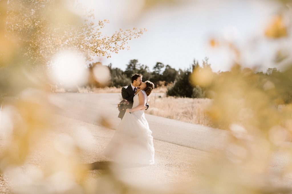 Bride and groom embracing and kissing along road